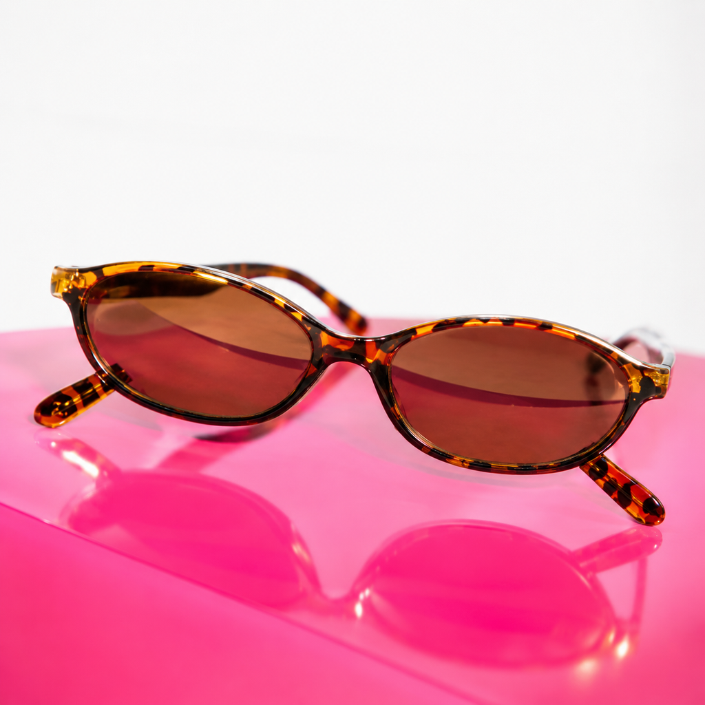 Sunglasses with tortoiseshell frame and brown lenses on a pink surface