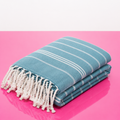 Stack of blue towels with white fringes on a pink background