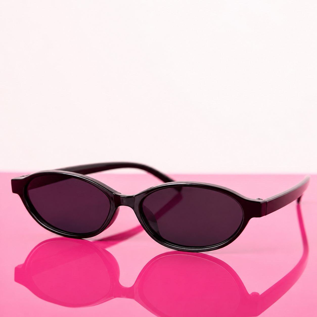 Black sunglasses with dark lenses on a pink surface
